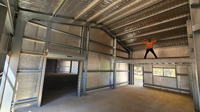 Interior of a large steel frame shed with reflective insulation installed on the walls and ceiling