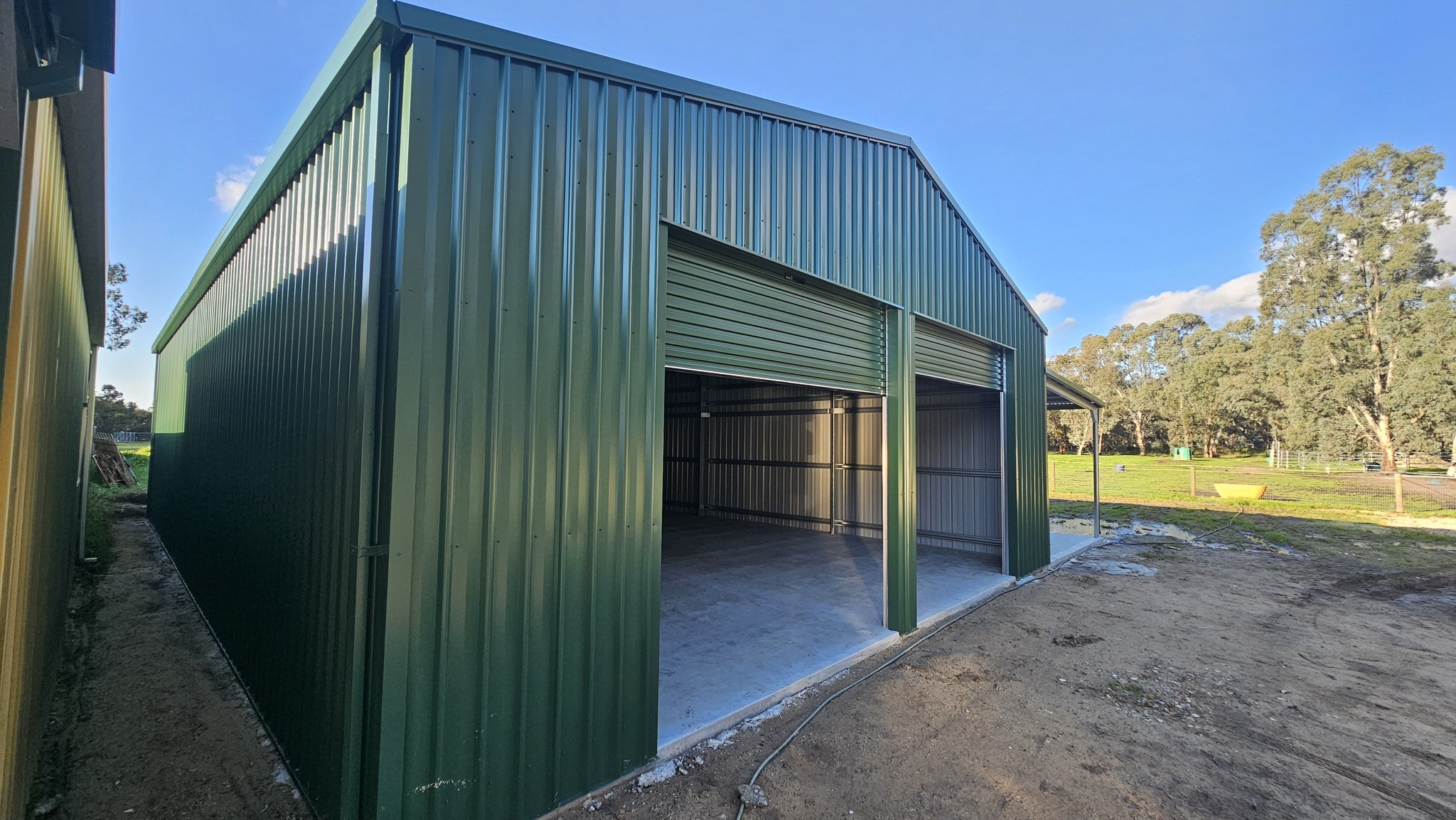 metal-shed-with-two-open-roller-doors green metal shed with two open roller doors