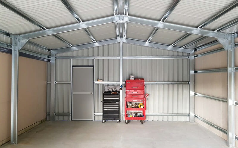 Shed interior featuring a red rolling tool cabinet placed neatly between structural steel wall frames next to a closed door